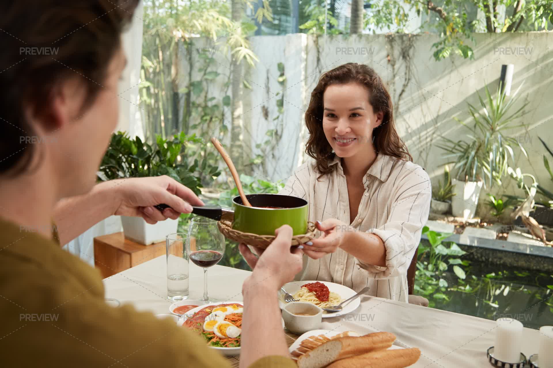 Smiling Woman Passing Saucepan With Pumpkin Purée To Partner At Dinner ...