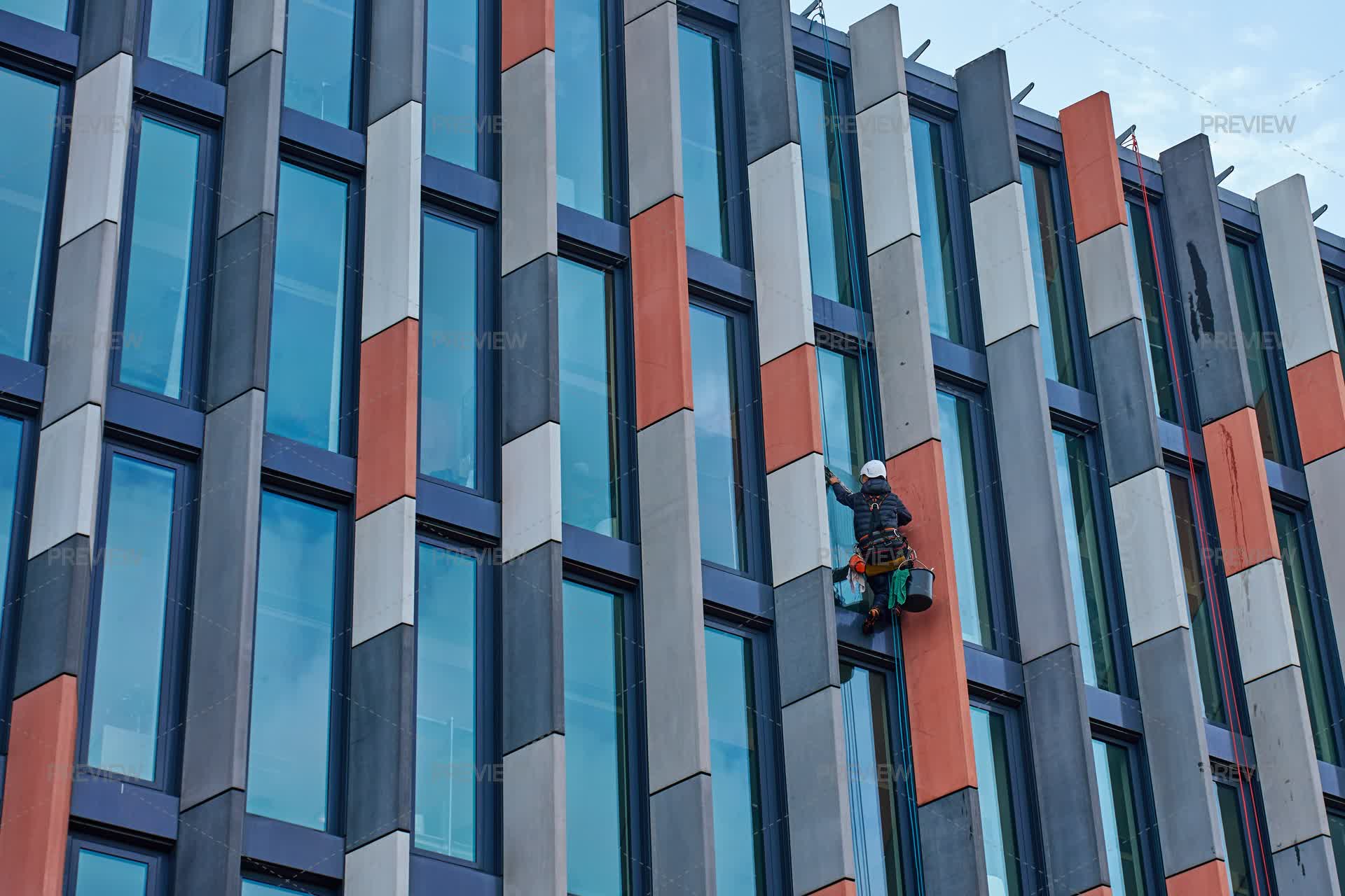 High Rise Worker Cleaning Windows On Modern Building Facade - Stock ...